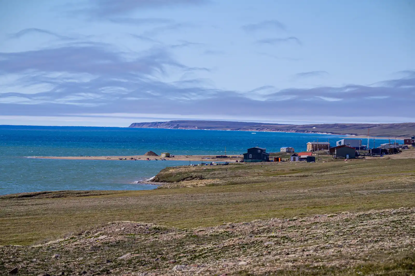 The sea off Ikaahuk (Sachs Harbour), Banks Island, deep blue under a summer sky, with the community on the shore.